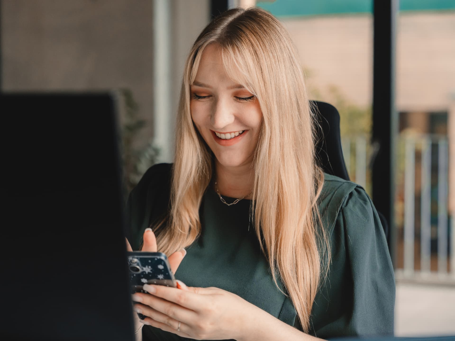 Mitarbeiterin von Euphoris Digital betreut lachend Social-Media-Kanäle am Smartphone