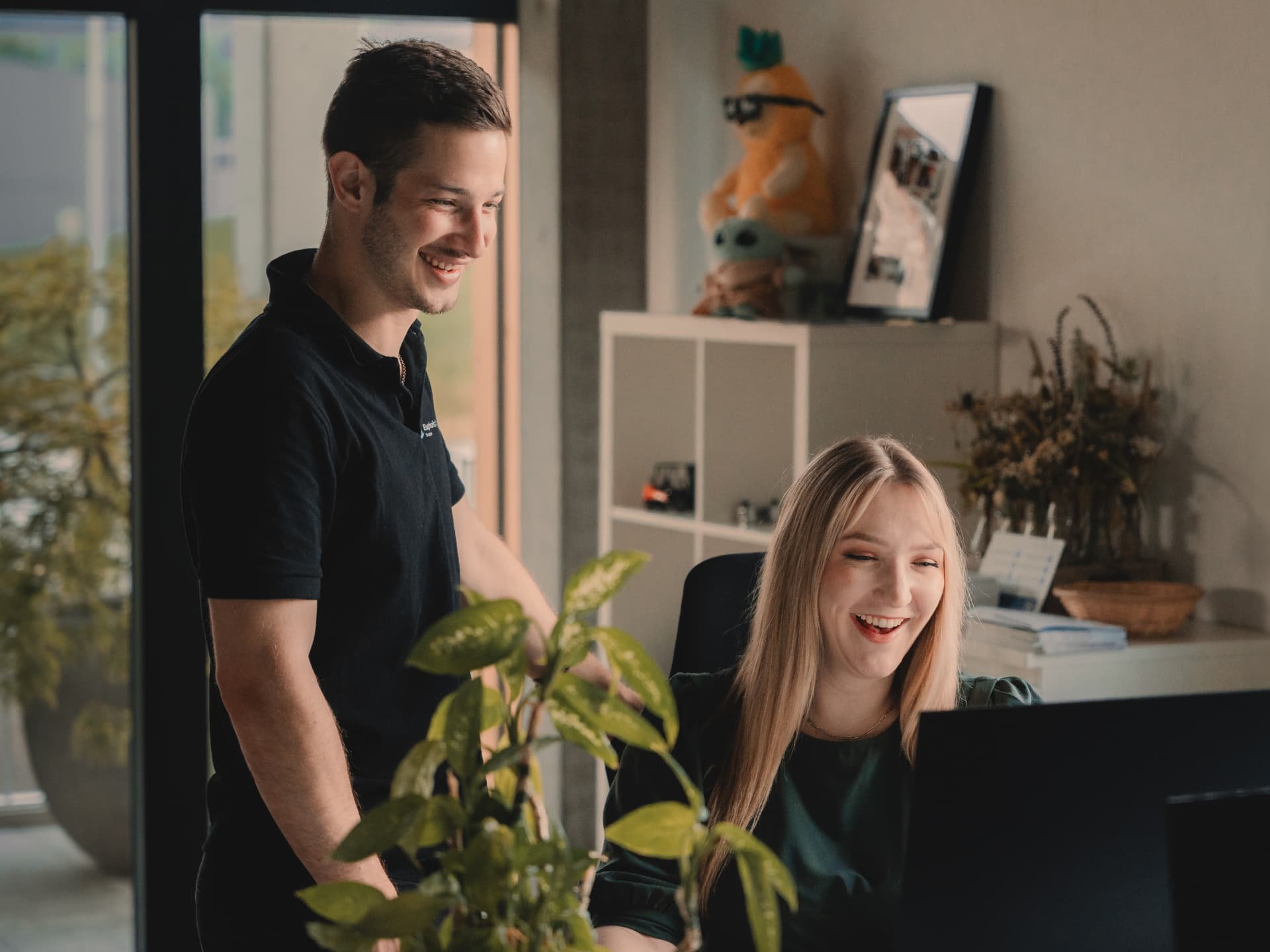 Zwei Mitarbeiter von Euphoris Digital lachen gemeinsam am Arbeitsplatz im Büro